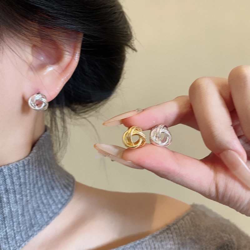Gold knot stud earrings worn on ear