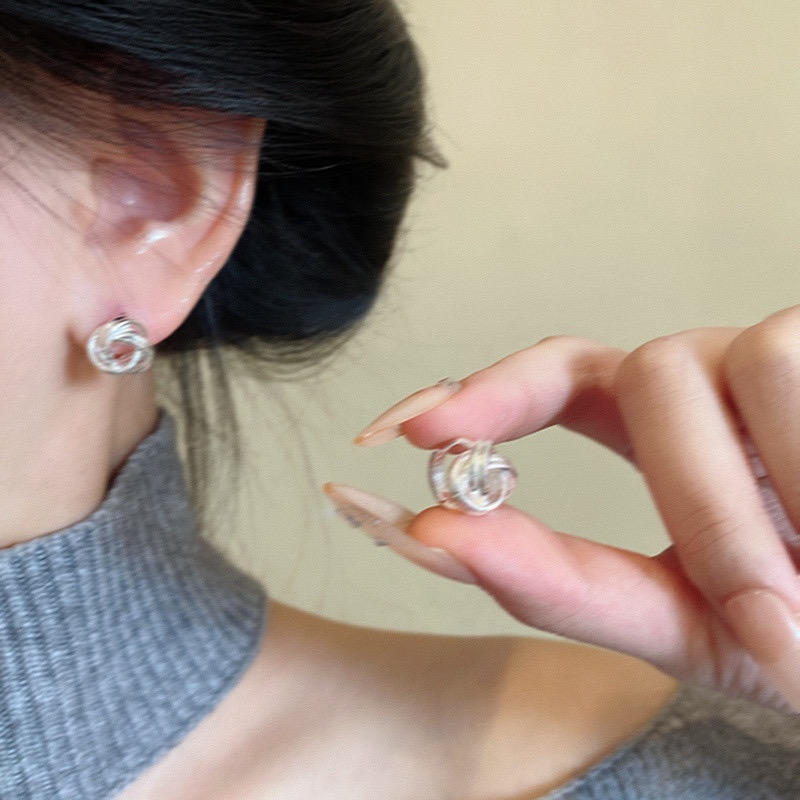 Silver knot stud earrings worn and held in hand