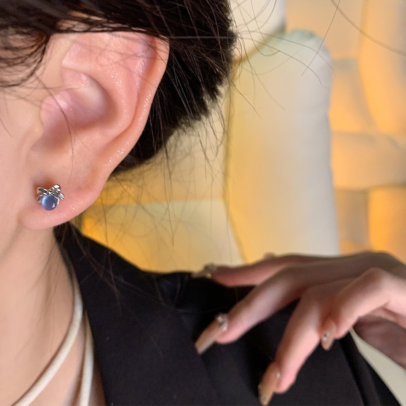 Blue cat eye bow stud earrings worn on ear