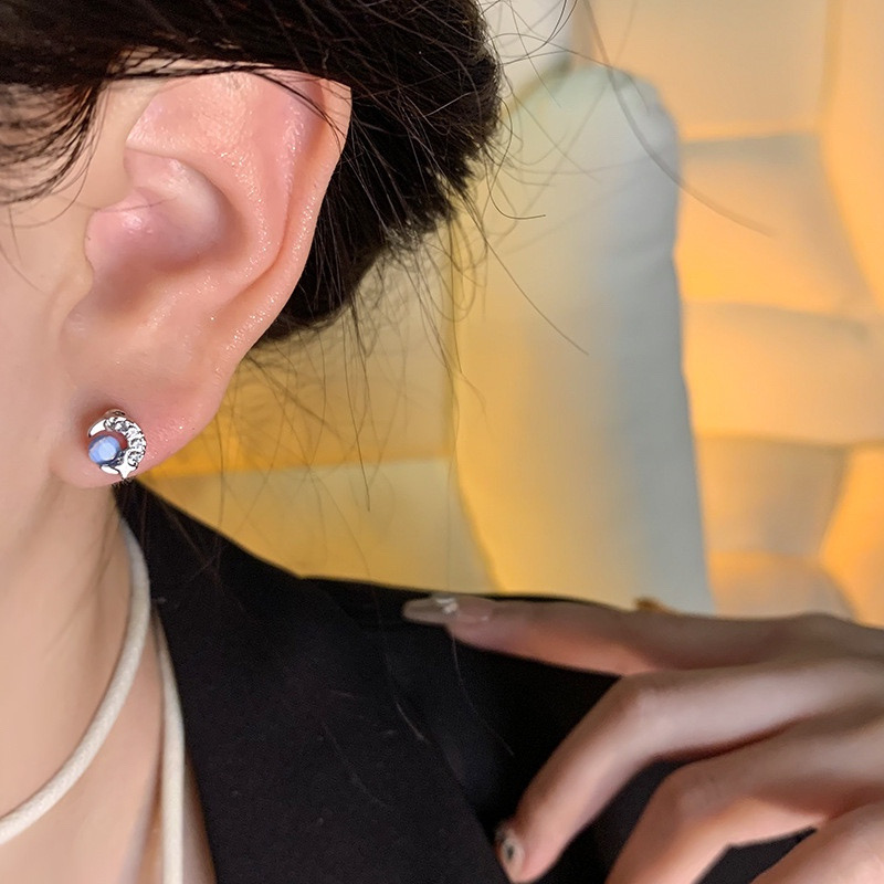 Blue cat eye crescent moon stud earrings worn on ear