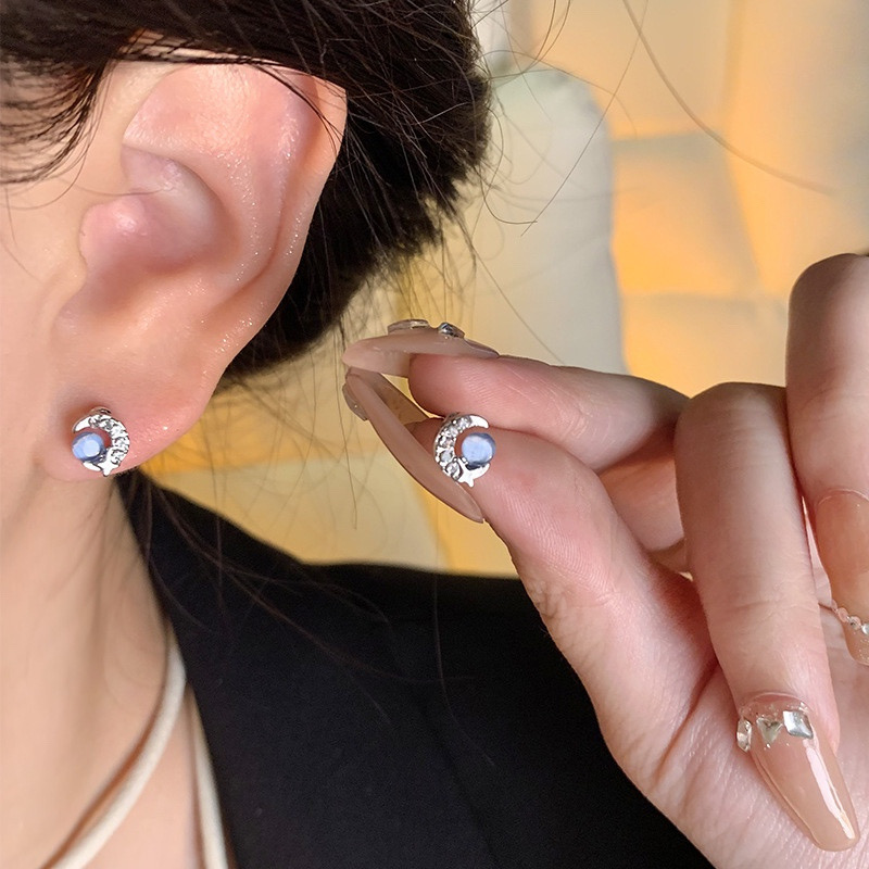 Blue cat eye crescent moon earrings worn and held in hand