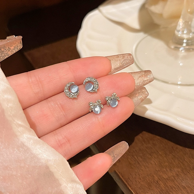 Blue cat eye bow and moon stud earrings close-up