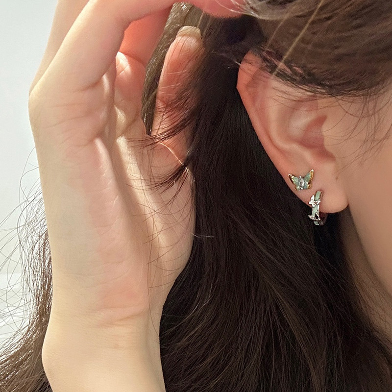 Silver blue butterfly hoop earrings worn on ear
