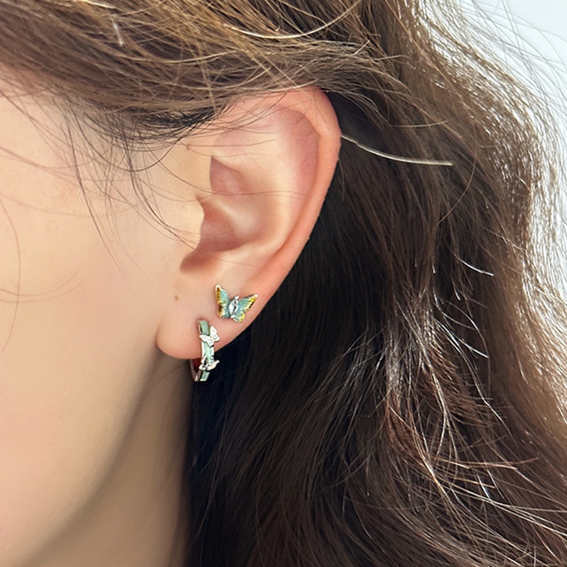 Small silver blue butterfly hoop earrings on ear