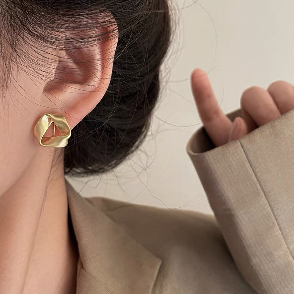 Gold twisted geometric earrings worn by model