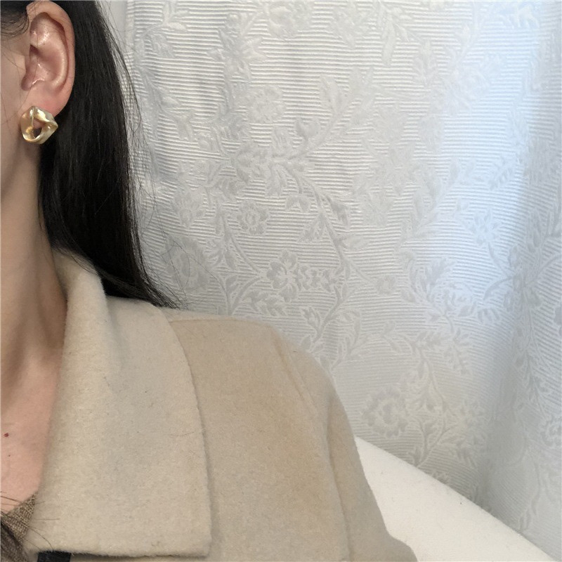Gold geometric earrings worn with neutral outfit