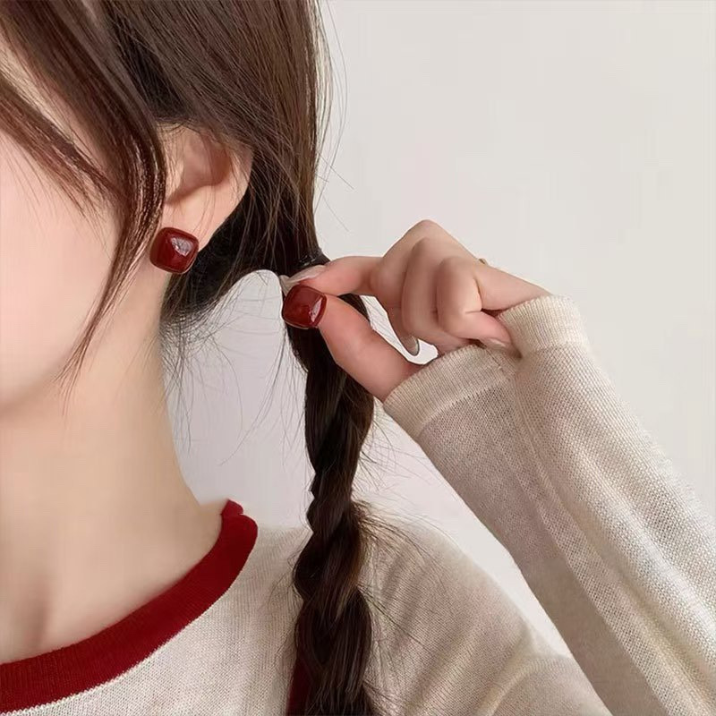 Burgundy enamel stud earrings styled on model