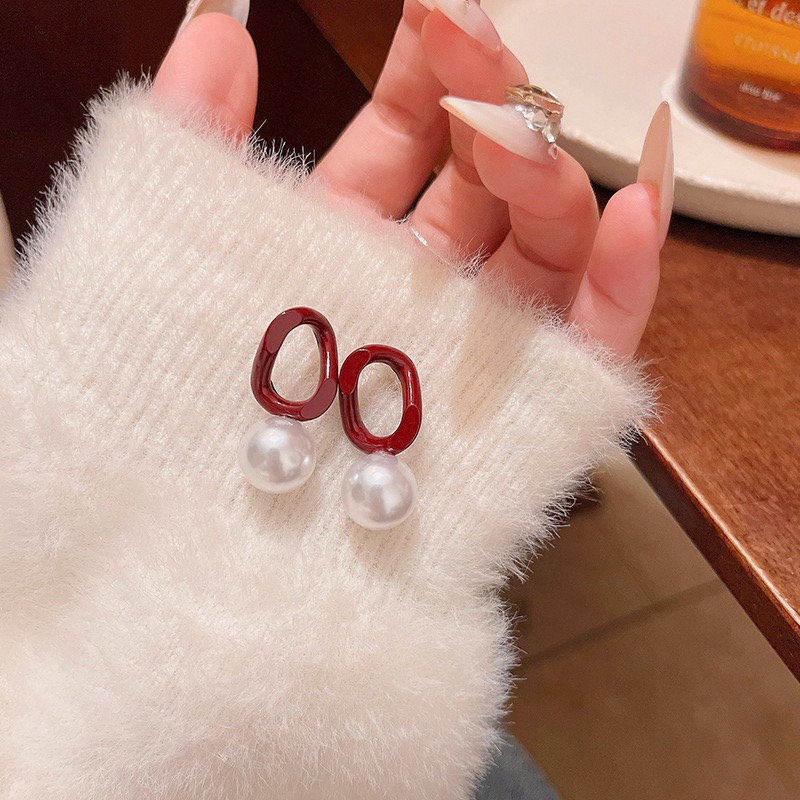 Burgundy pearl drop earrings displayed on sleeve