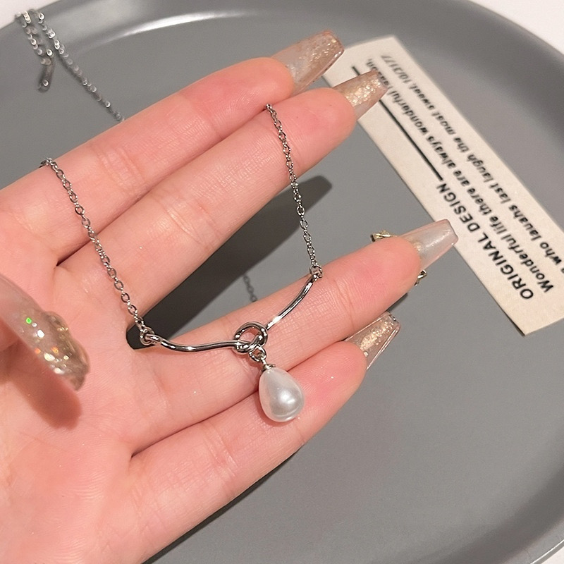 Silver Tone Faux Pearl Pendant Necklace Held Above Gray Display Tray