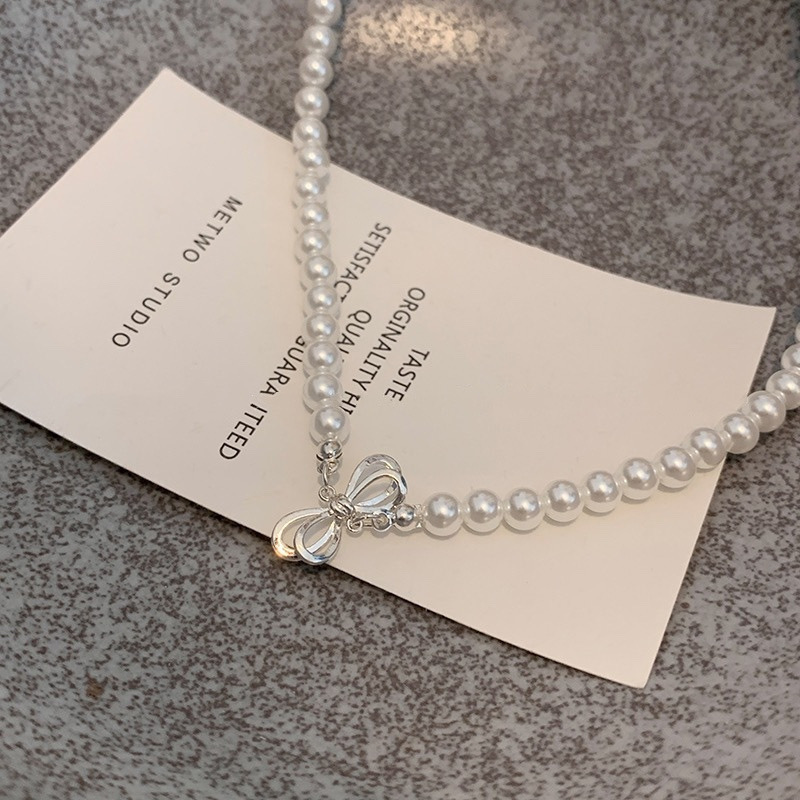 Close Up of Silver Tone Bow Charm and White Faux Pearls on Choker Necklace