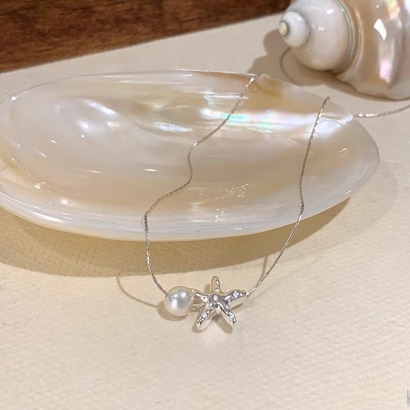 Silver Tone Starfish and White Faux Pearl Necklace Displayed on Shell Dish