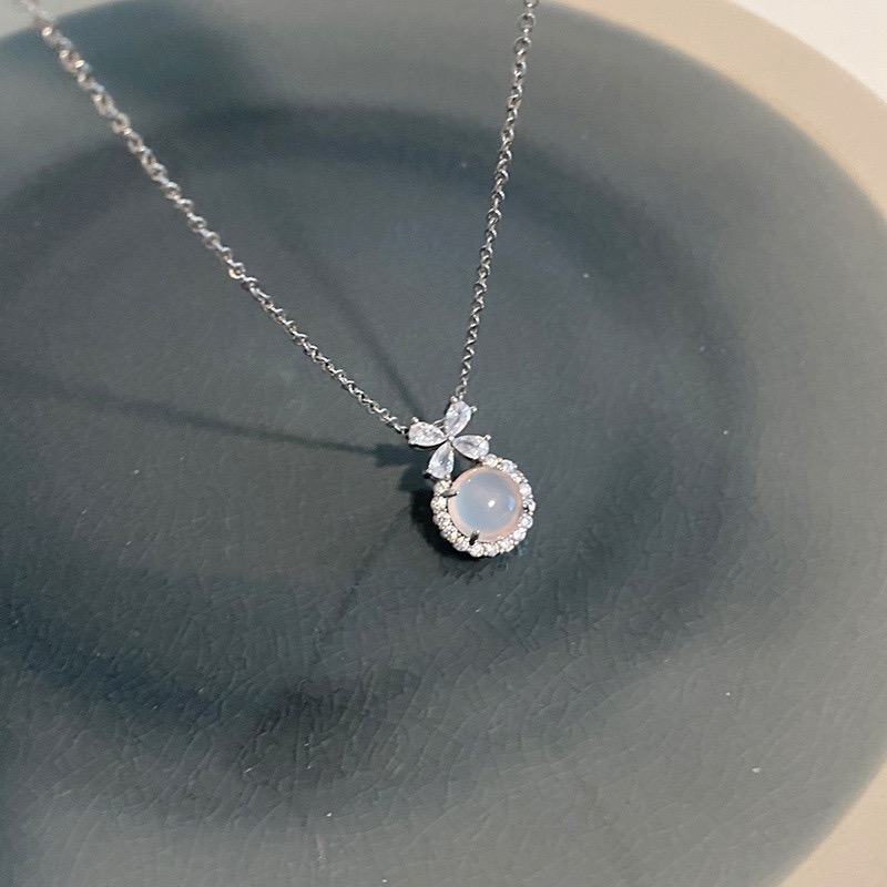 Silver Floral White Stone Pendant Necklace Displayed on Dark Gray Surface