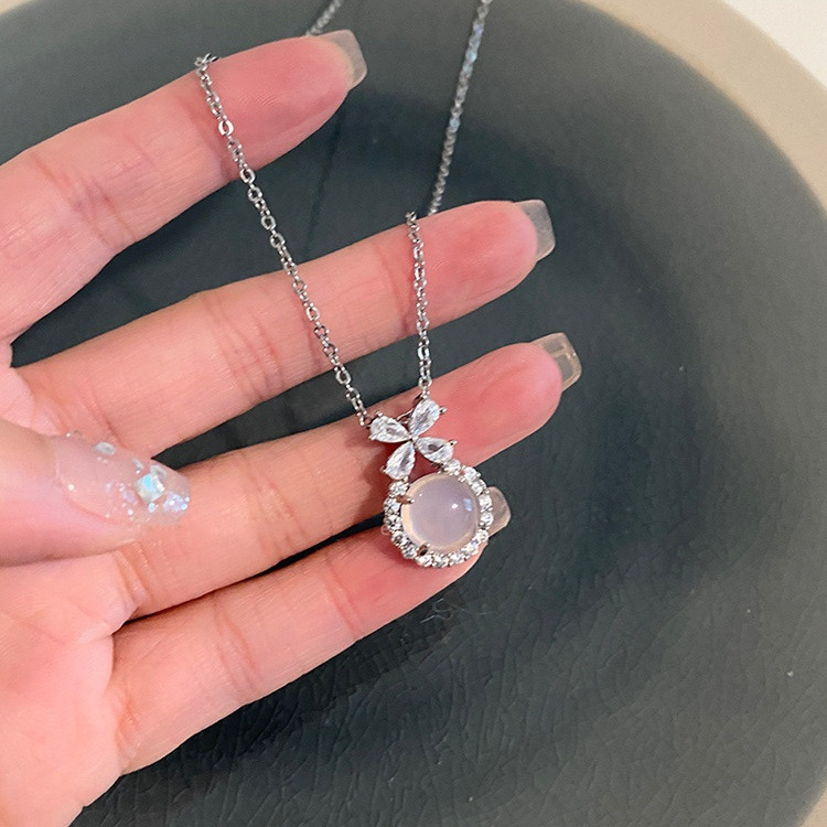 Close-Up of Silver Floral Pendant Necklace with Luminous White Centerpiece Held in Hand