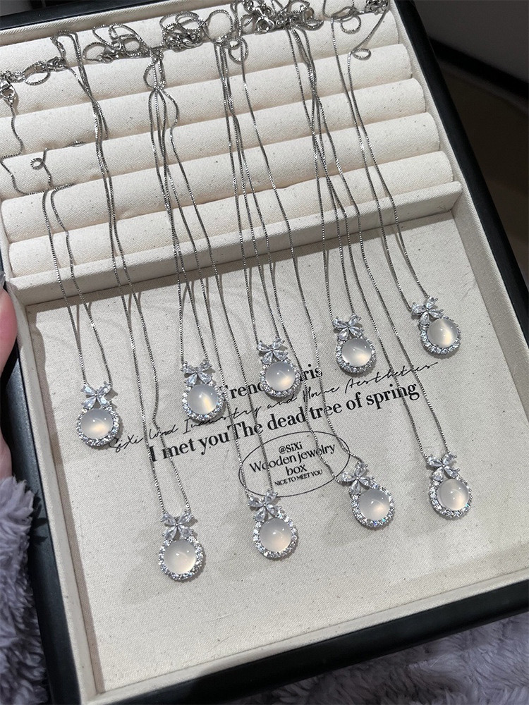 Multiple Silver Floral White Stone Pendant Necklaces Arranged on Jewelry Display Tray