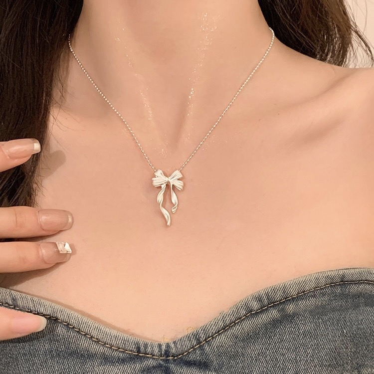 Silver ribbon bow pendant necklace styled with a denim outfit for an elegant everyday jewelry look