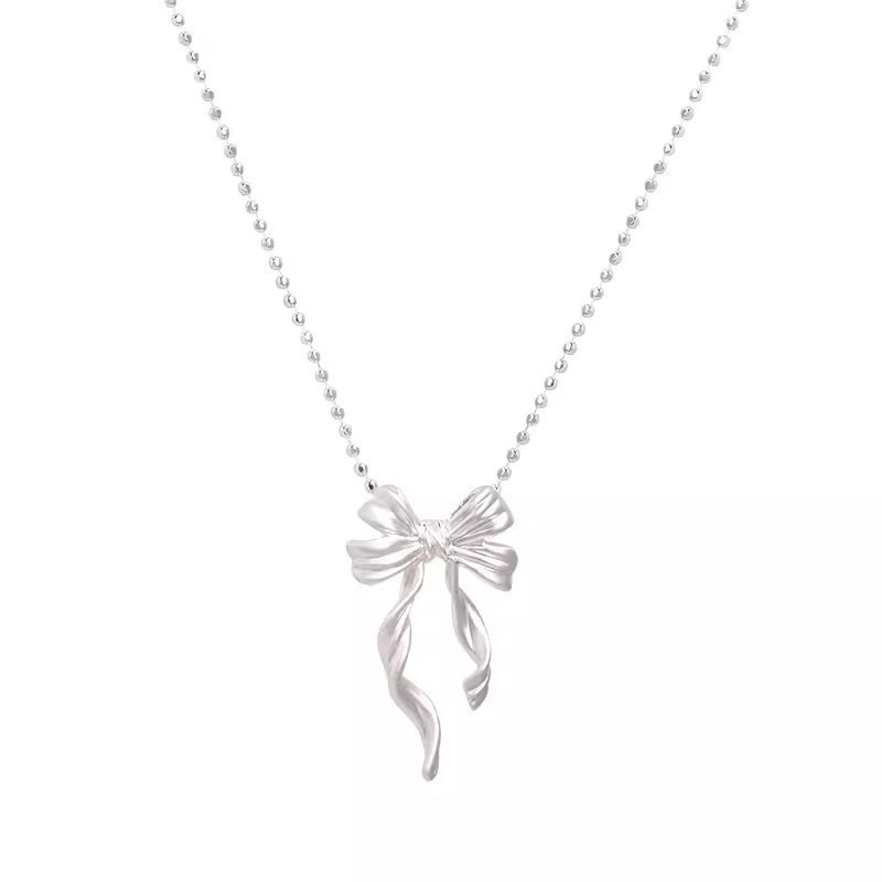 Silver ribbon bow pendant necklace with flowing ribbon tails and delicate beaded chain on white background