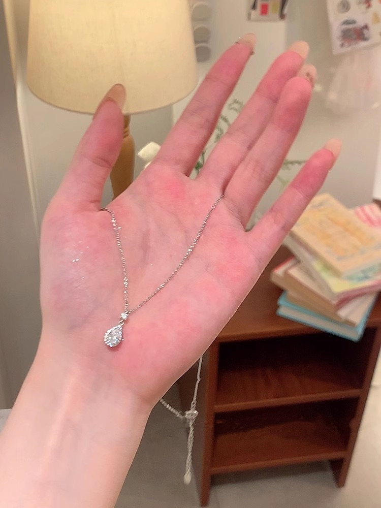 Delicate silver zircon teardrop pendant necklace displayed on an open palm showing pendant size and chain