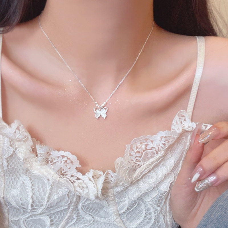 Silver butterfly pendant necklace with white cat eye stone styled with a delicate white lace top
