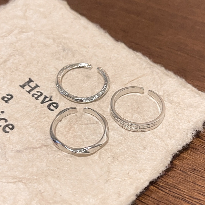 Three Minimalist Silver Rings on Soft Fabric
