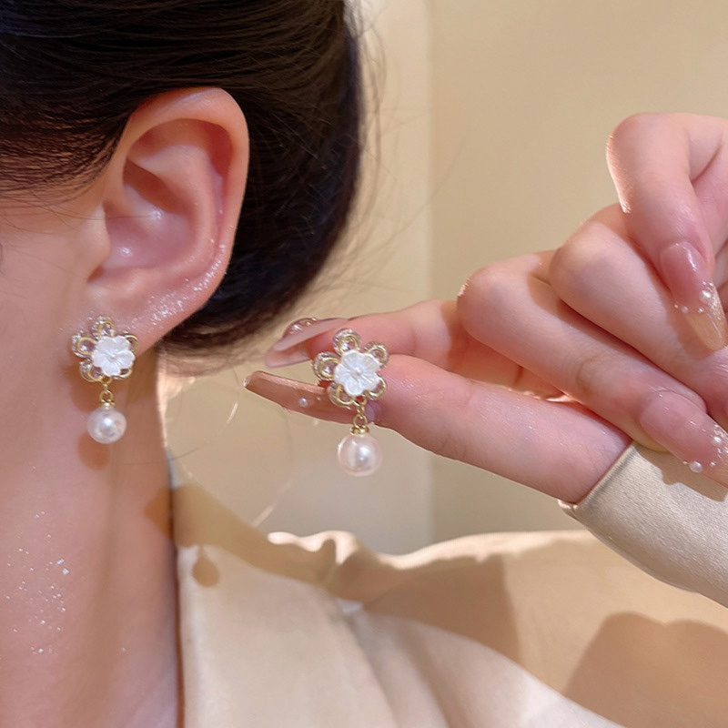 Gold pearl flower earrings worn and held in hand