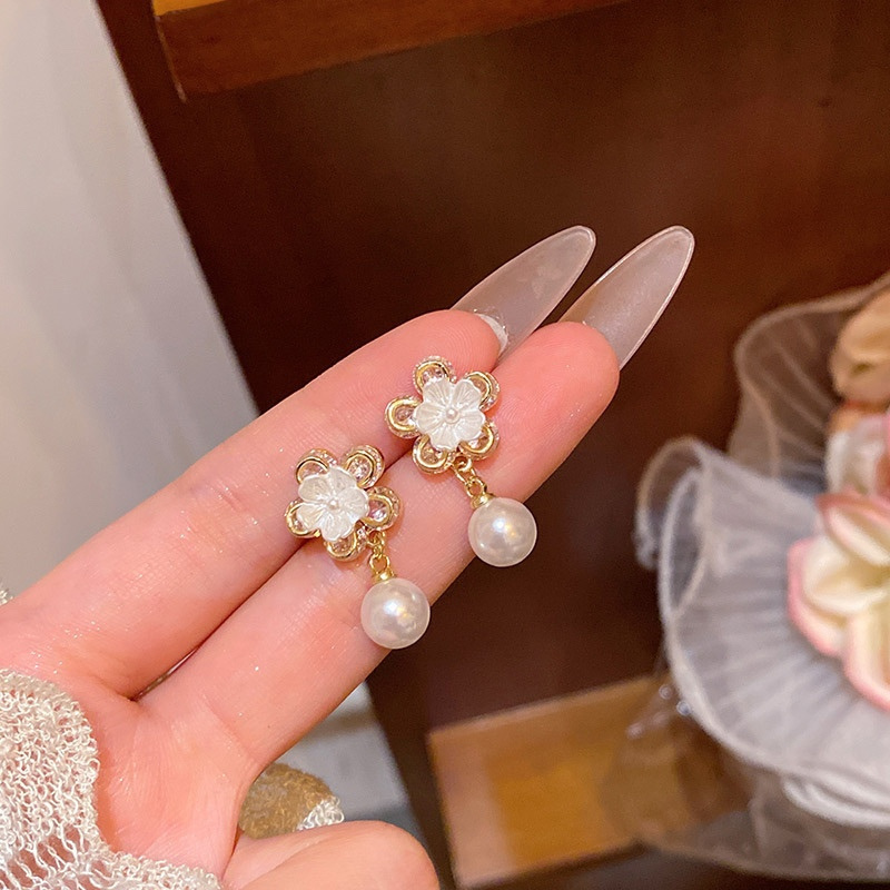 Gold flower pearl drop earrings pair close-up