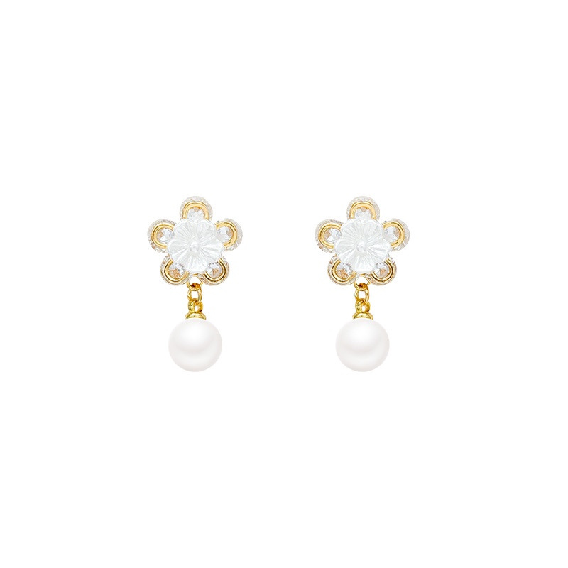 Gold floral pearl drop earrings on white background