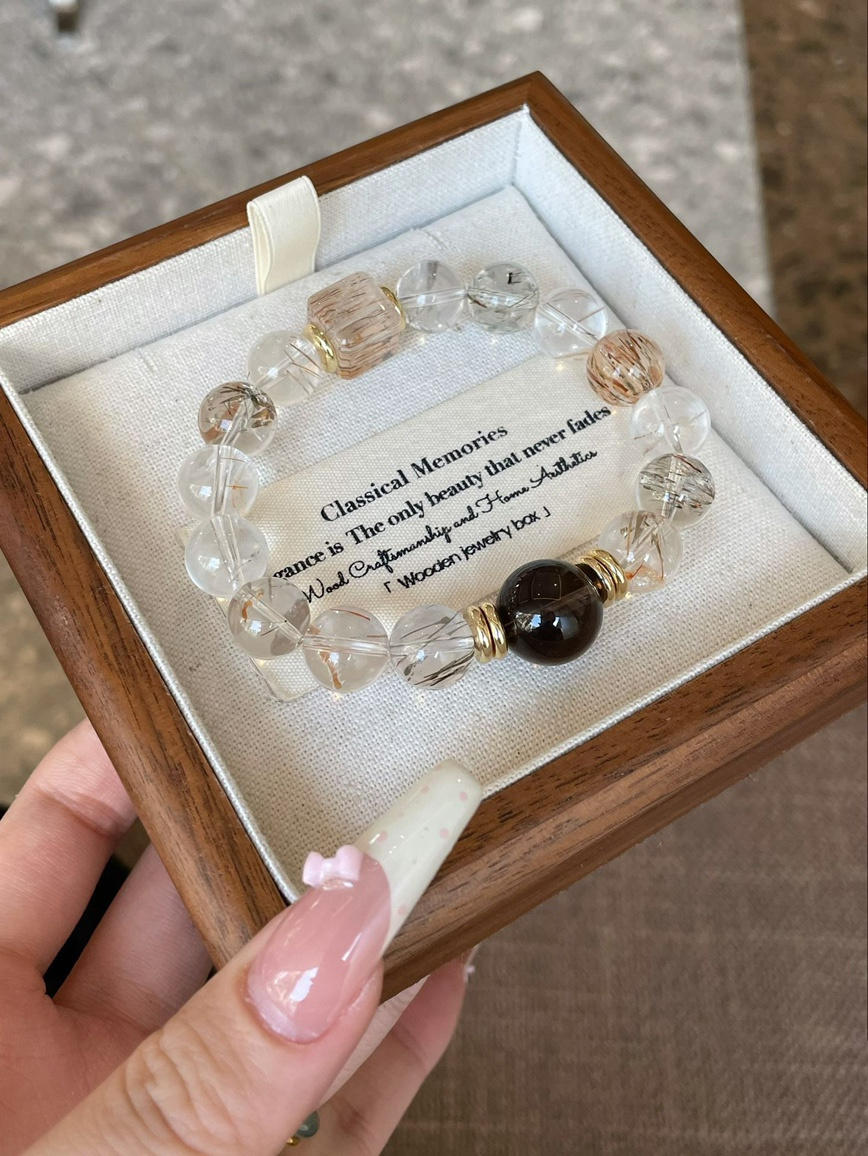 Golden rutilated quartz bracelet displayed in a wooden jewelry box