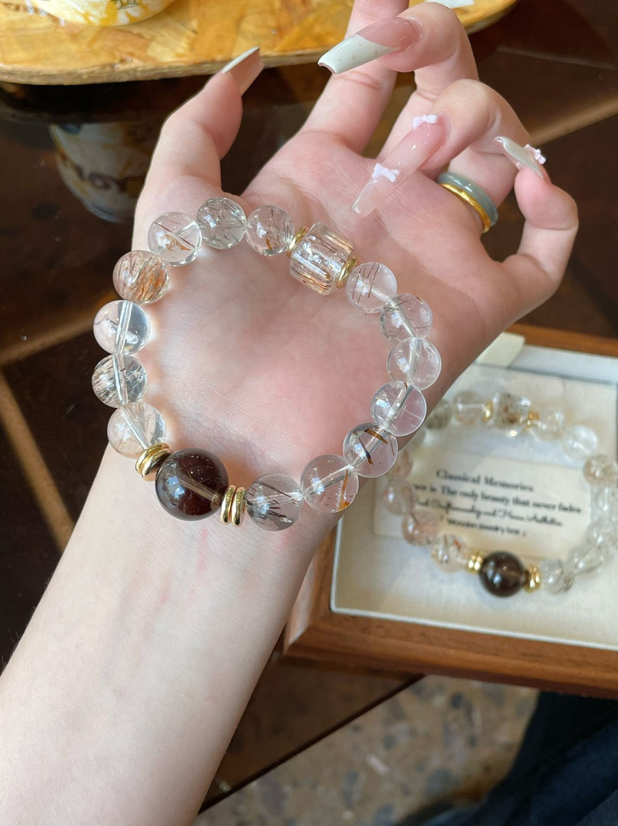 Rutilated Quartz and Smoky Quartz bracelet held in hand under natural light