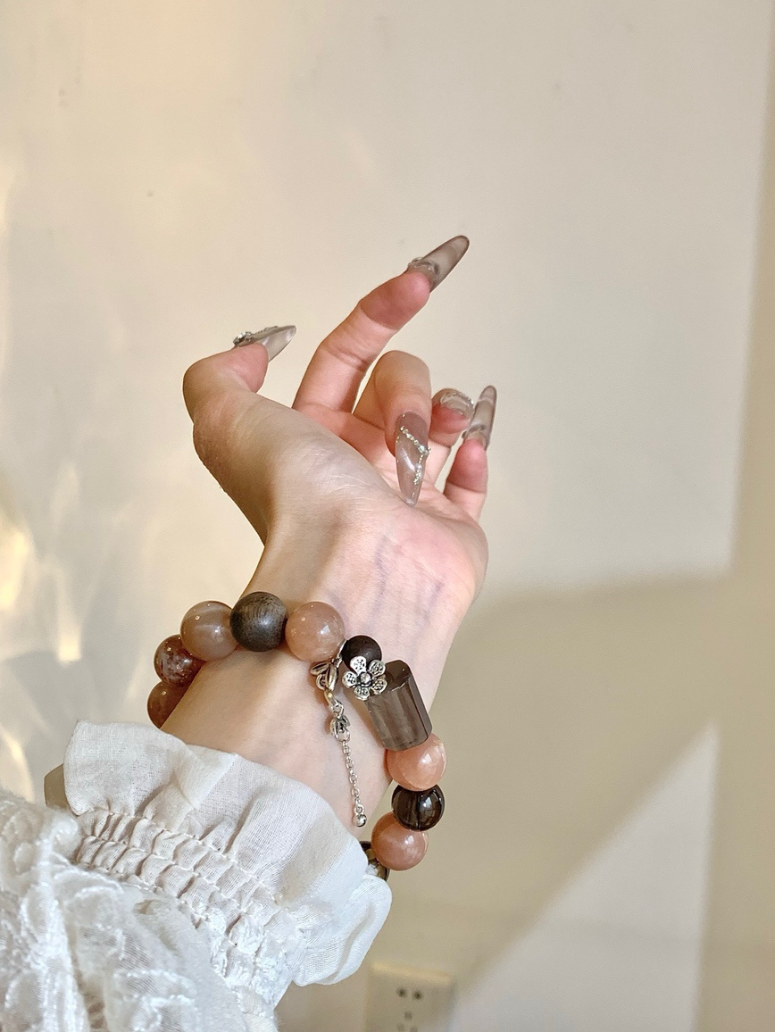 Model wearing moonstone and smoky quartz bracelet on wrist in natural light