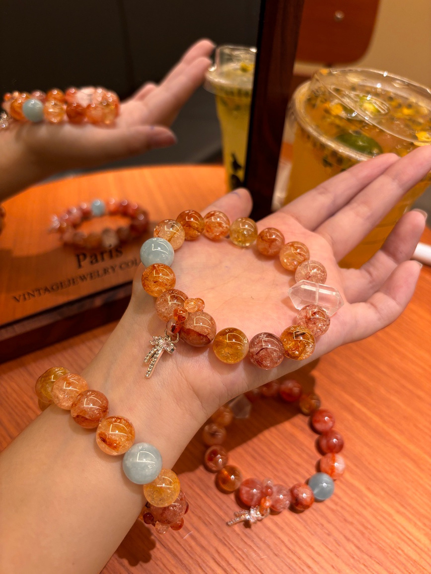 Red flower crystal bracelet with aquamarine and clear quartz charm worn on wrist