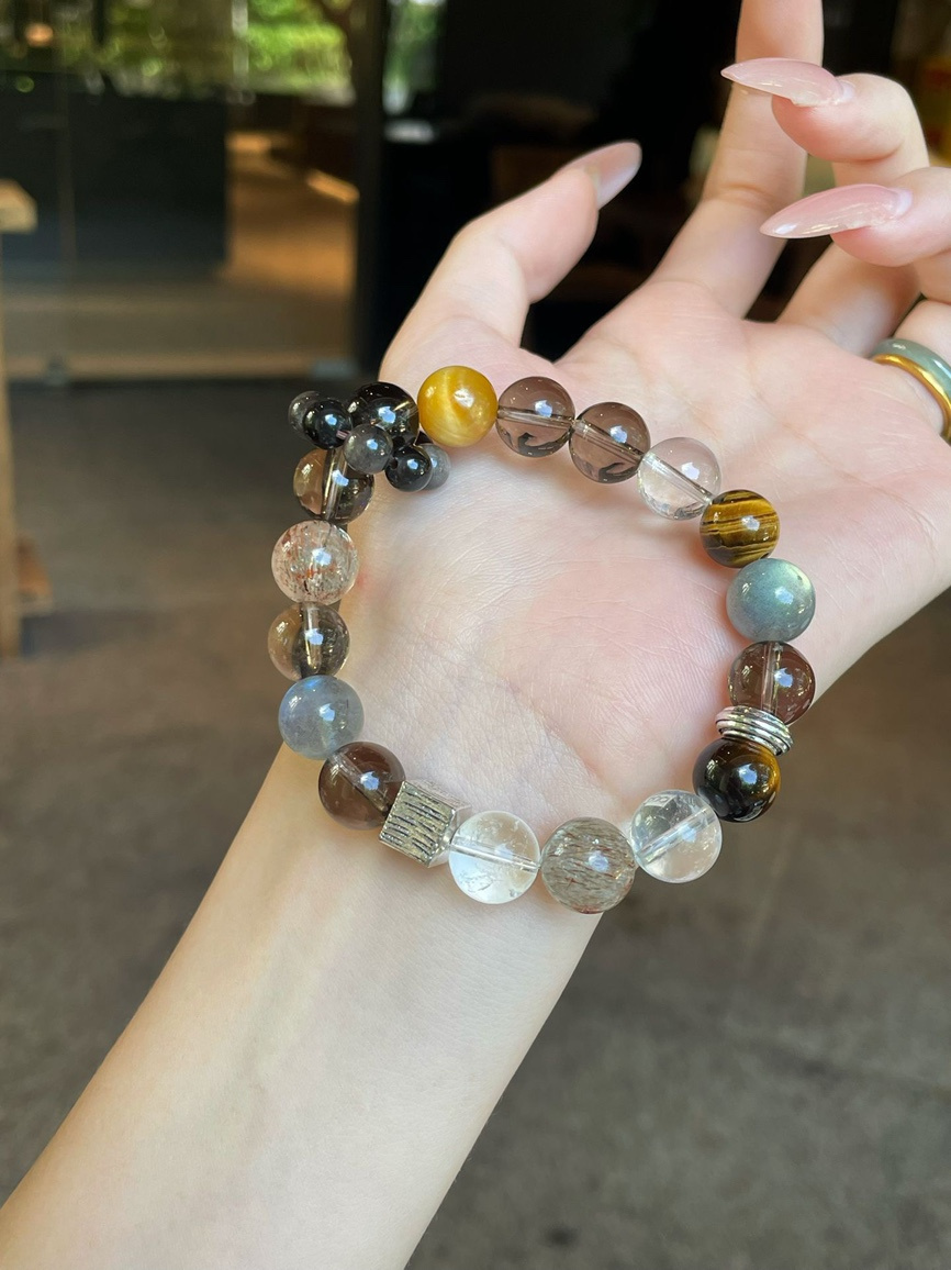 Wrist wearing natural gemstone bracelet with warm brown and golden tones.
