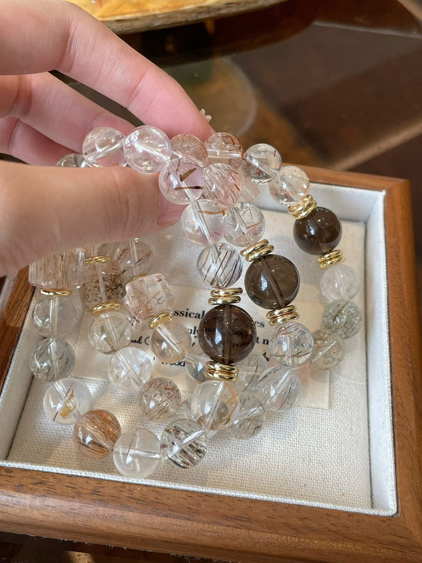 Stacked clear quartz and smoky quartz bracelets with soft lighting