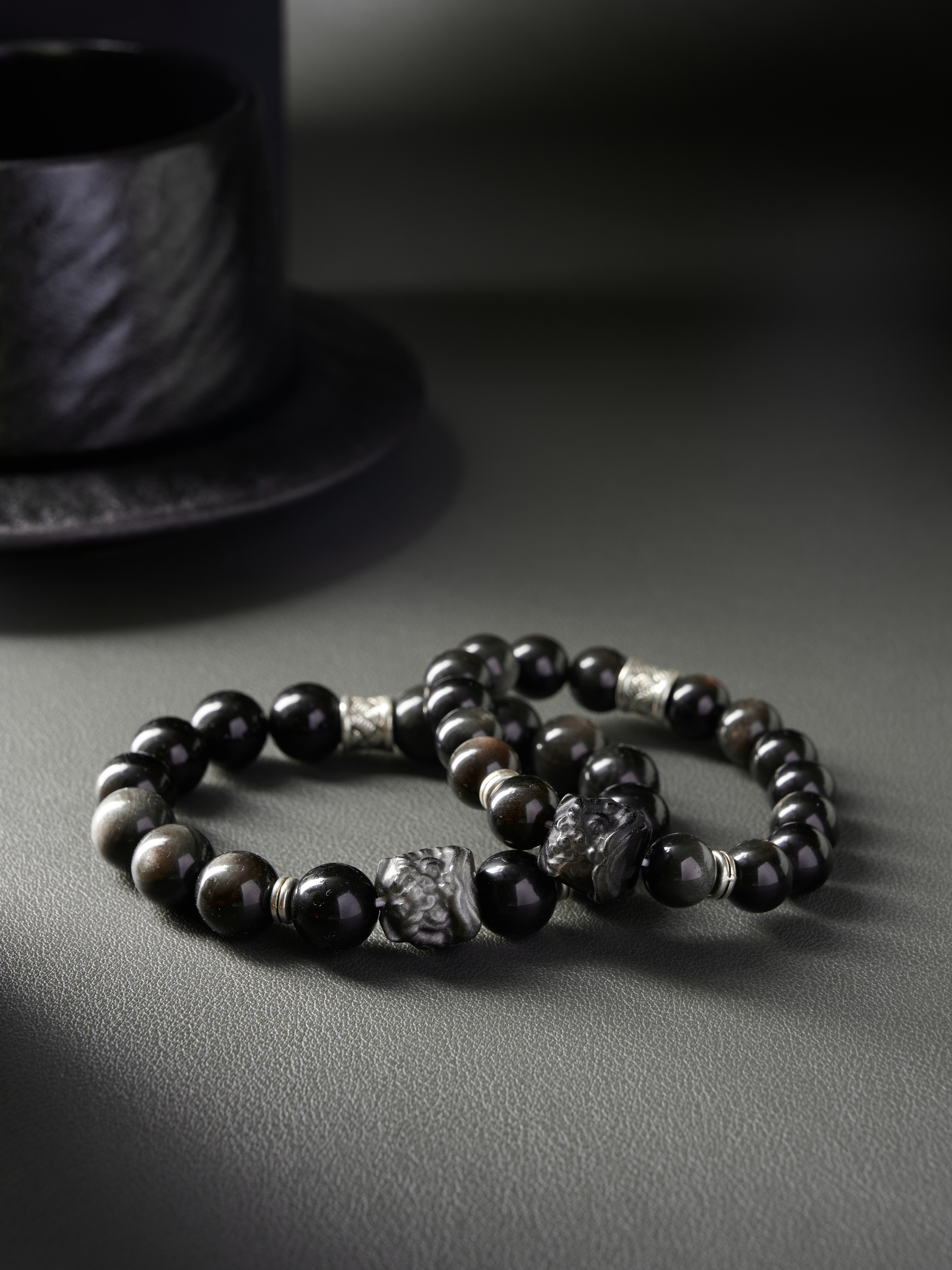 AvigJewelry obsidian couple bracelets, carved focal bead and silver spacers, elastic 16–18 cm — full flat-lay top view