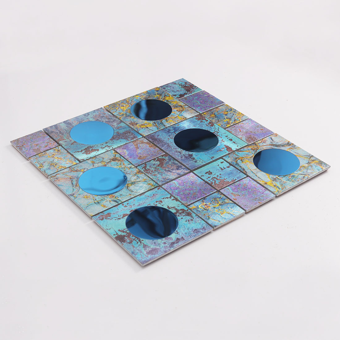 Angled view of blue round mirror glass and textured aluminum mosaic tile sheet