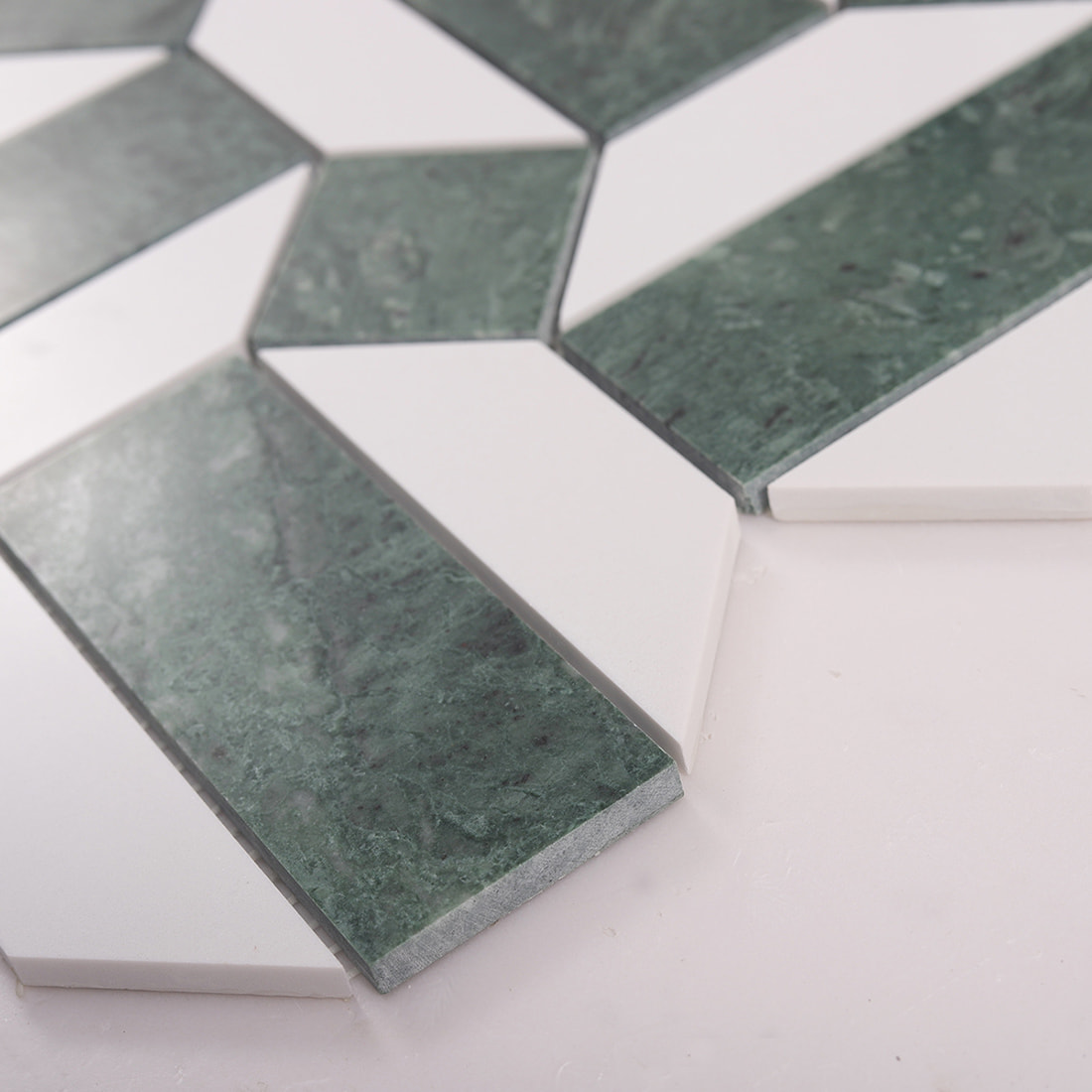 Angled view showing thickness and beveled edges of green and white marble mosaic tile