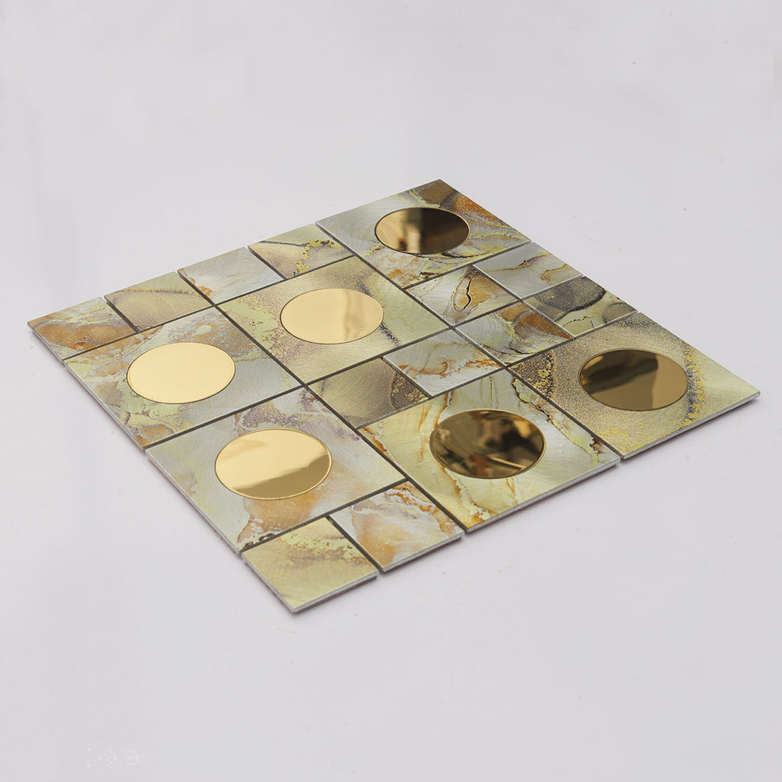 Angled view of gold round mirror glass and cream aluminum mosaic tile sheet