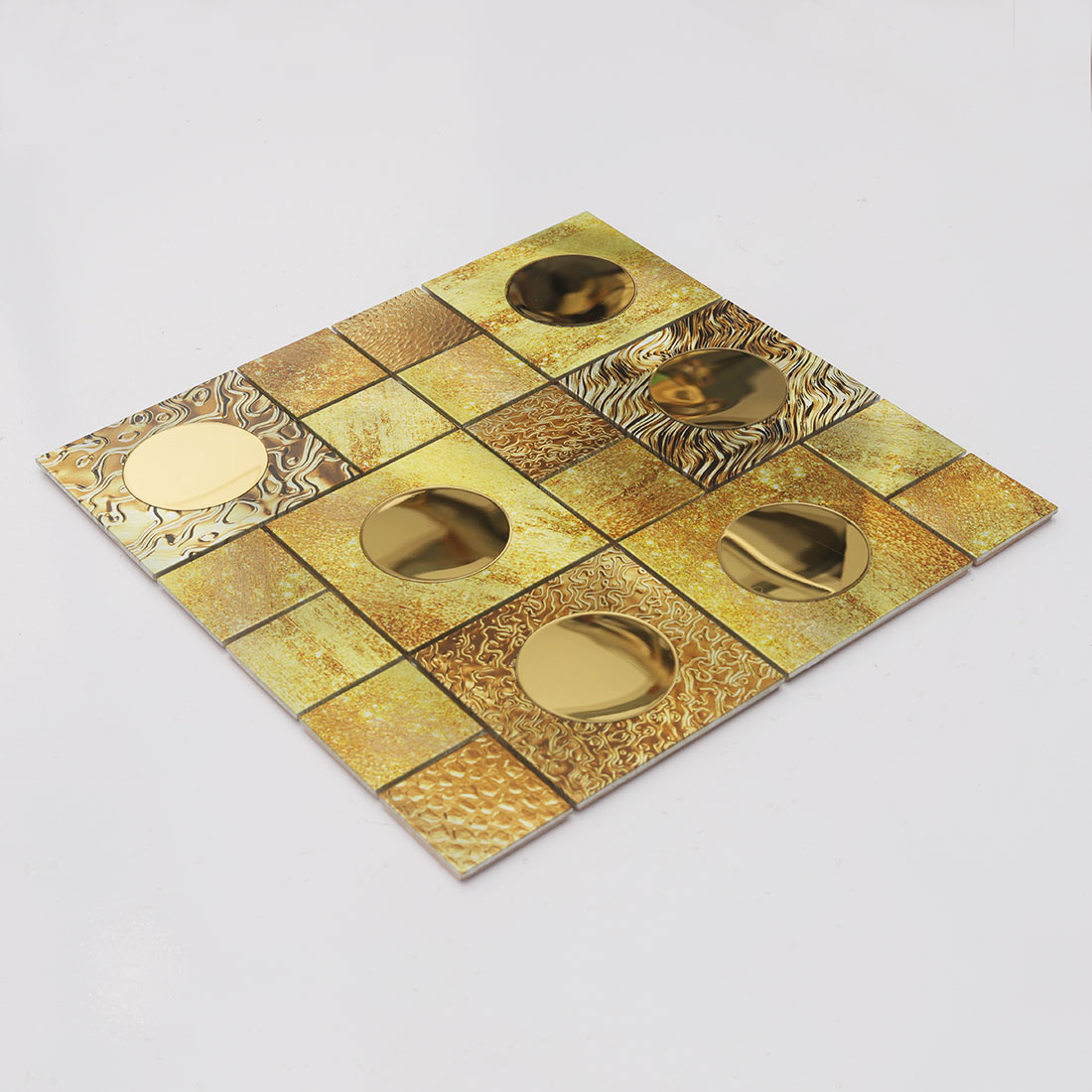Angled view of gold round mirror glass and textured metal mosaic tile sheet