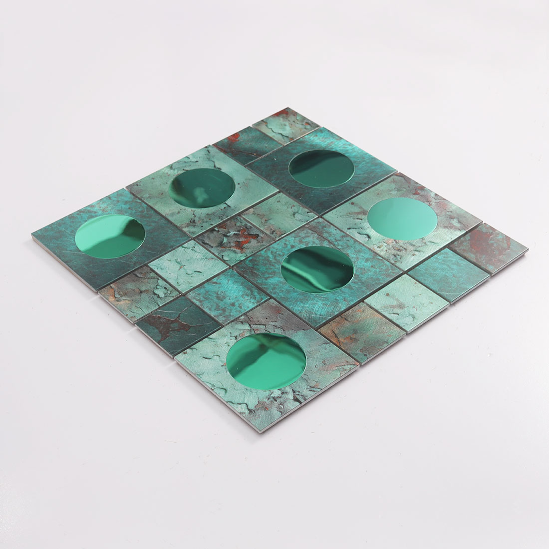 Angled view of green round mirror glass and textured aluminum mosaic tile sheet