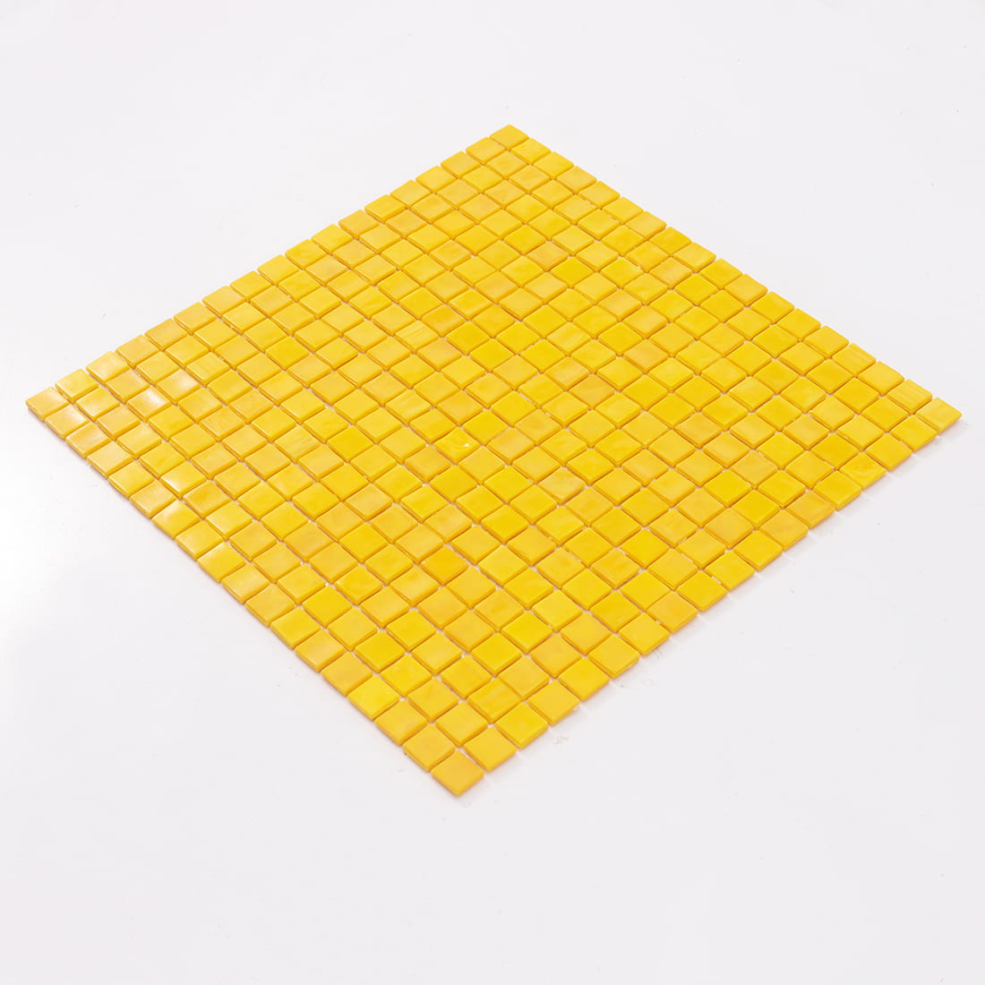 Angled view of bright yellow glass mosaic tile sheet on clean white background