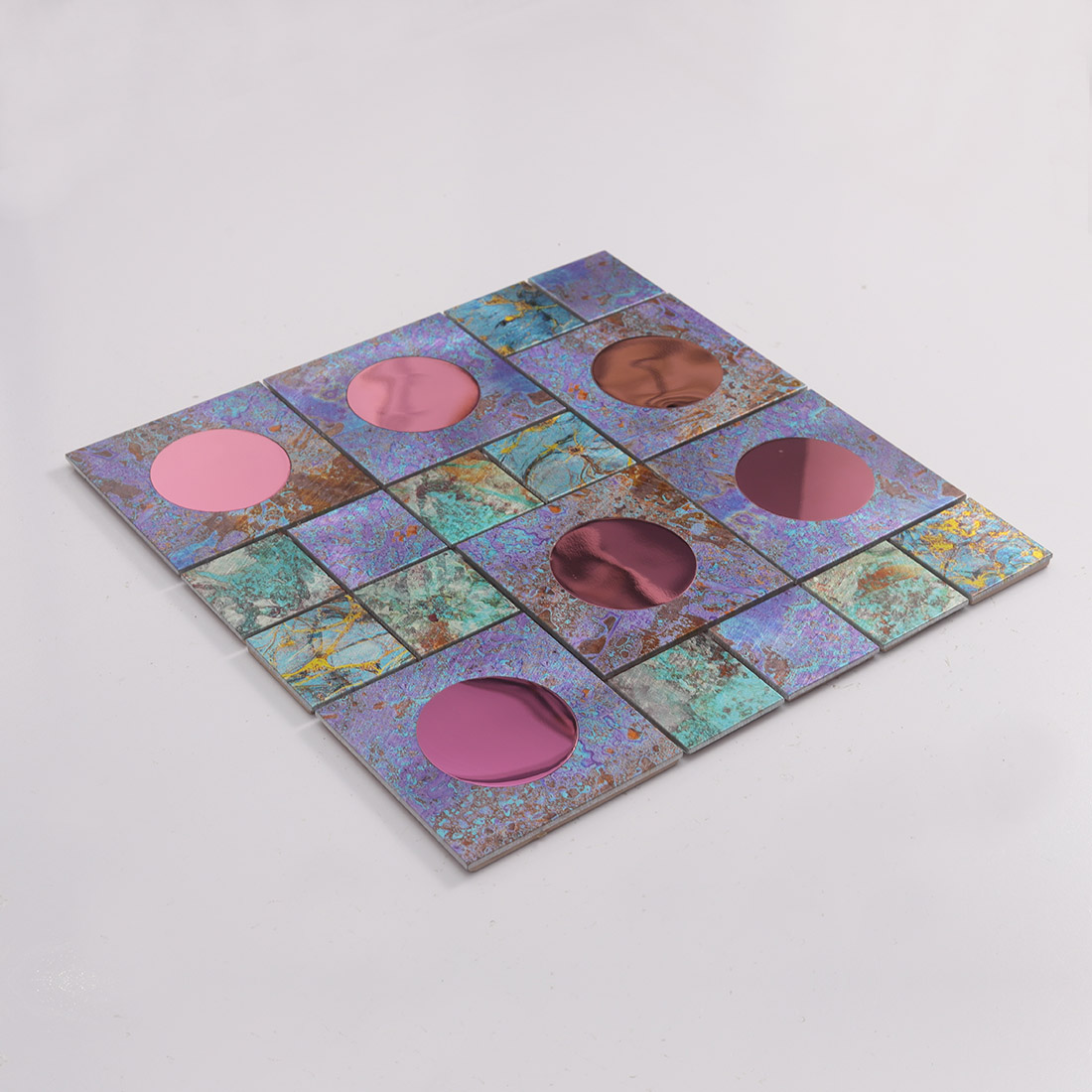 Angled view of pink mirror glass and iridescent metal mosaic tile sheet