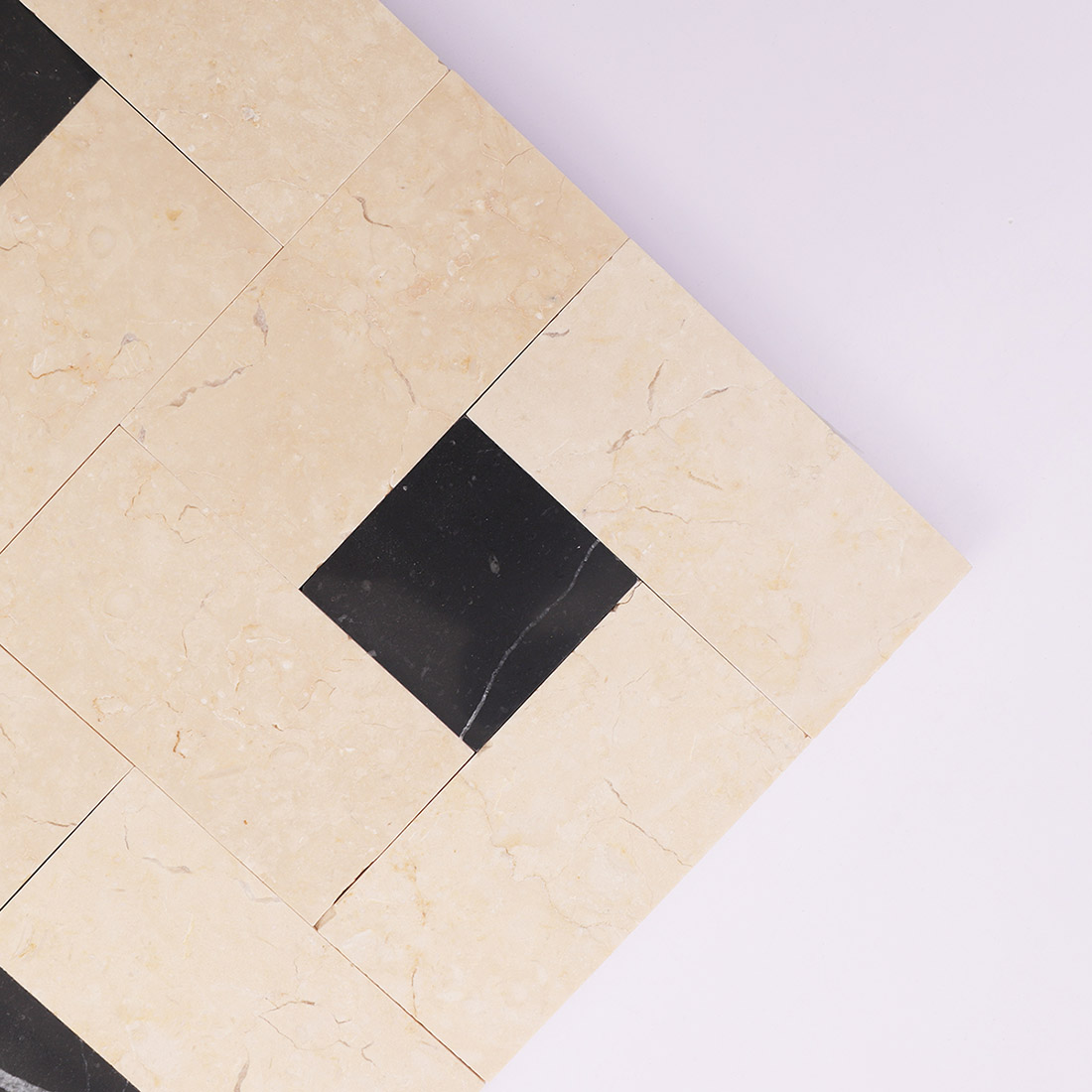 Corner detail of beige black marble mosaic tile with black square accents
