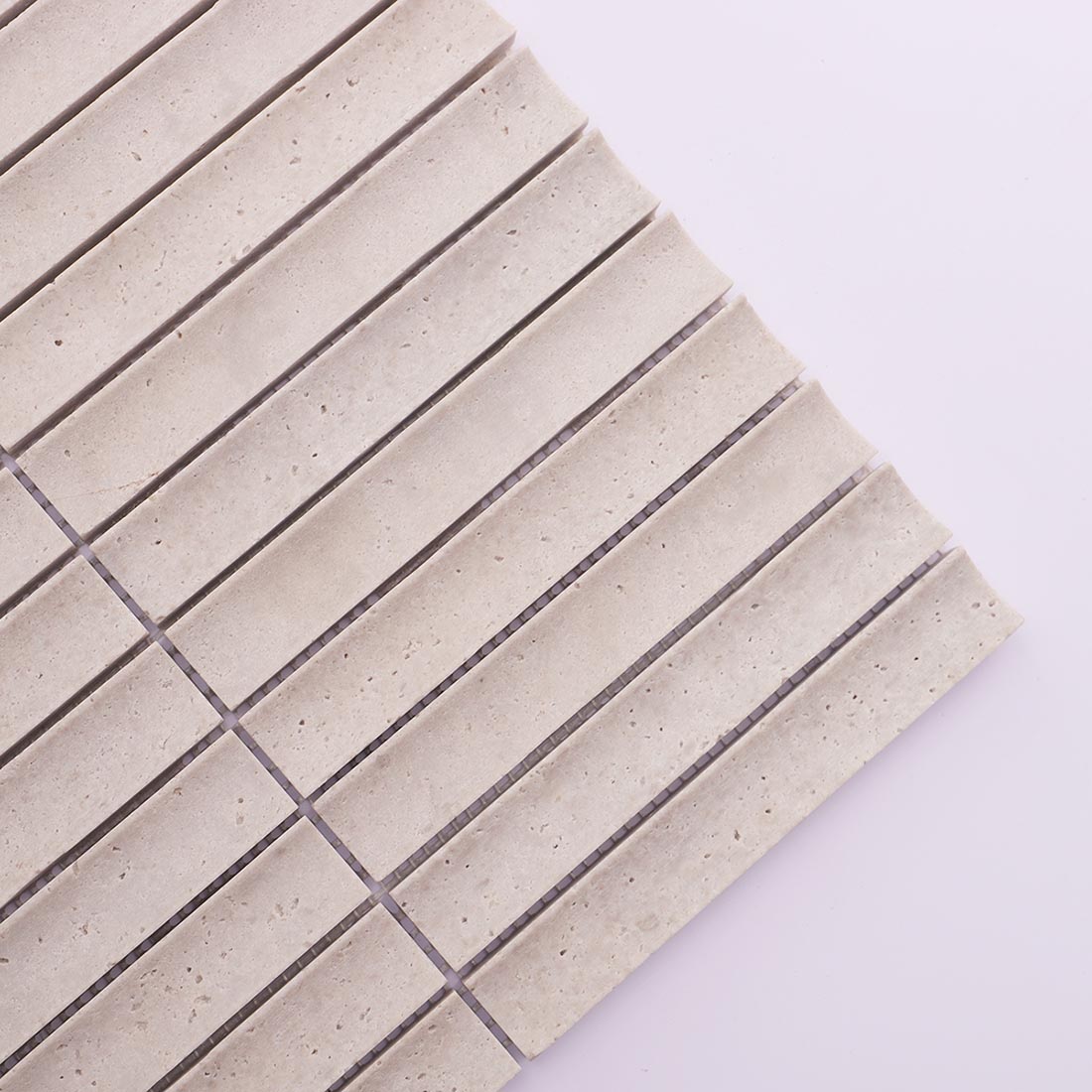 Corner detail of light gray grooved travertine mosaic tile with natural texture