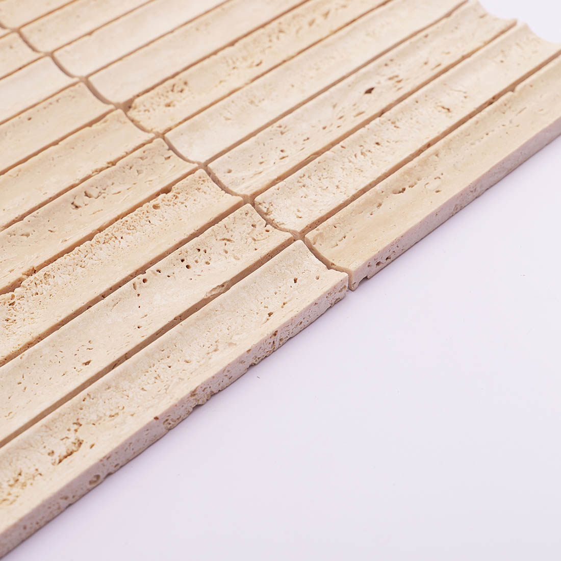 Side edge detail of beige grooved travertine mosaic tile with natural pores