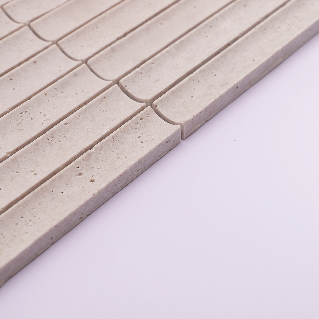 Side edge detail of light gray grooved travertine mosaic tile with natural pores