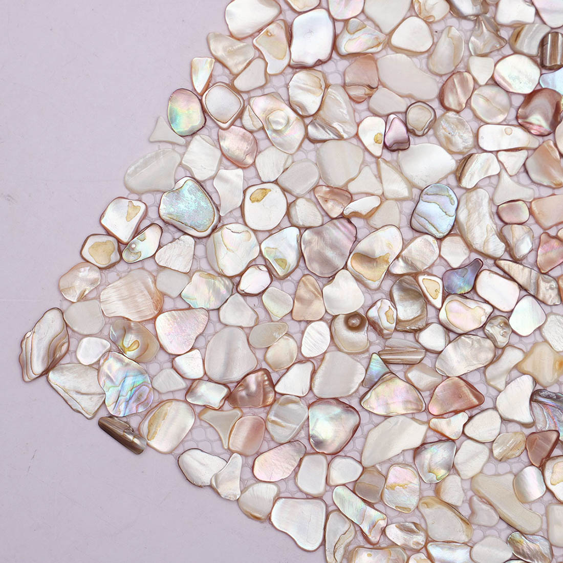 Detail view of irregular beige iridescent mother of pearl pebble mosaic pieces