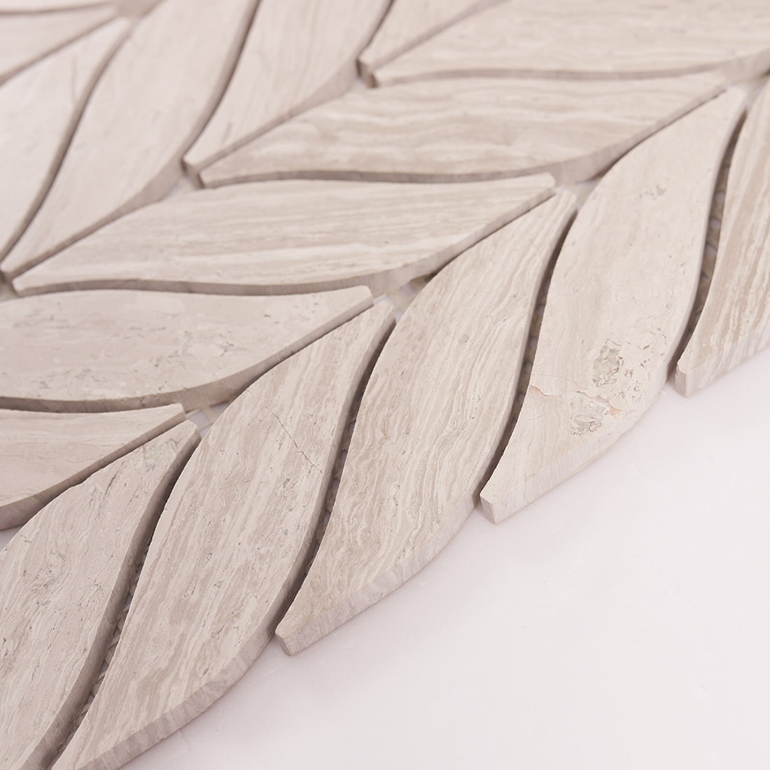 Angled view of beige marble leaf mosaic showing tile thickness and edges.