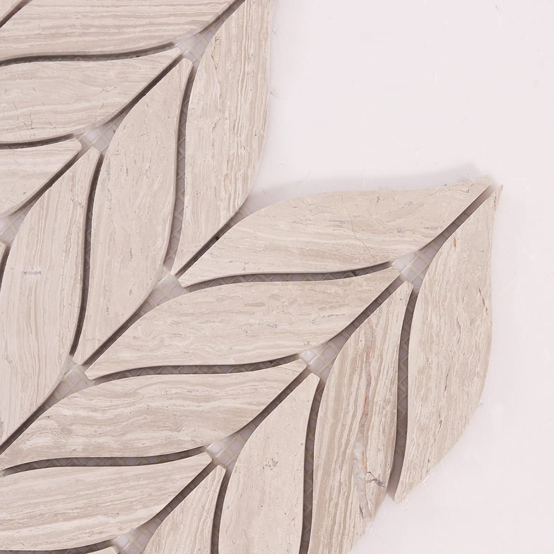 Corner close up of beige marble leaf mosaic showing grout gaps and alignment.