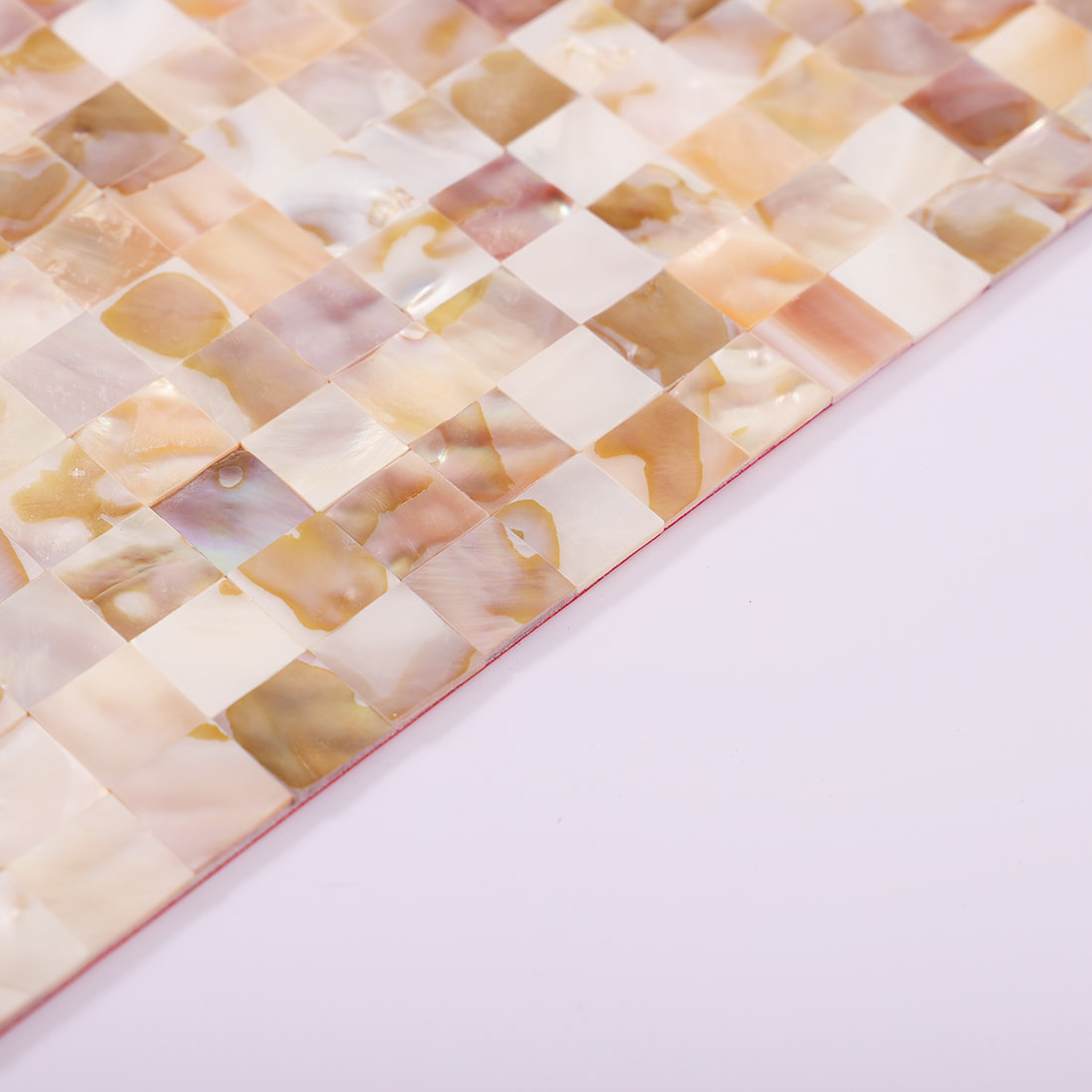 Angled edge detail of beige mother of pearl mosaic tile sheet on lavender background