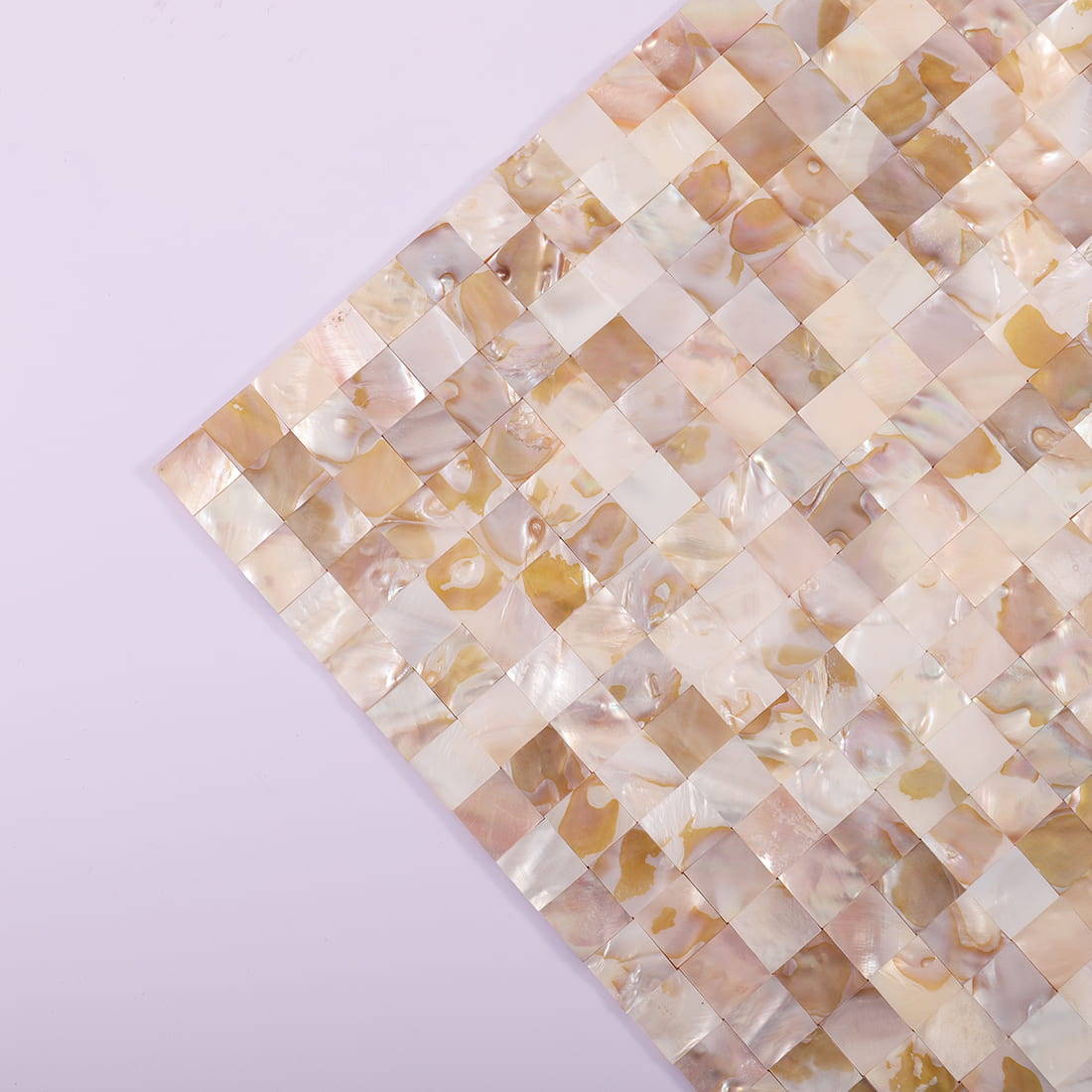 Corner view of beige mother of pearl mosaic tile sheet on lavender background