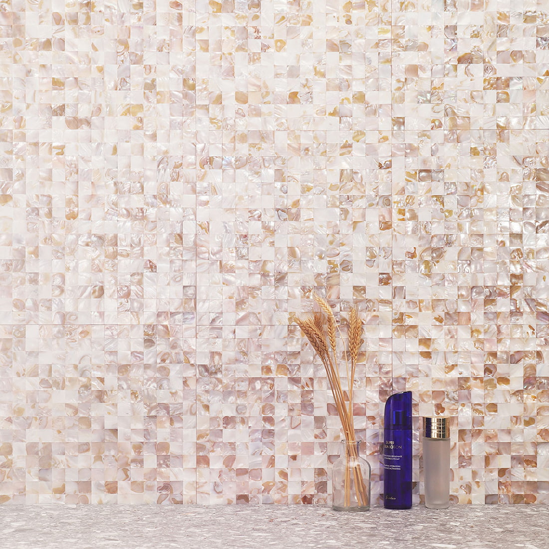 Beige natural shell mosaic wall styled with wheat and decorative bottles